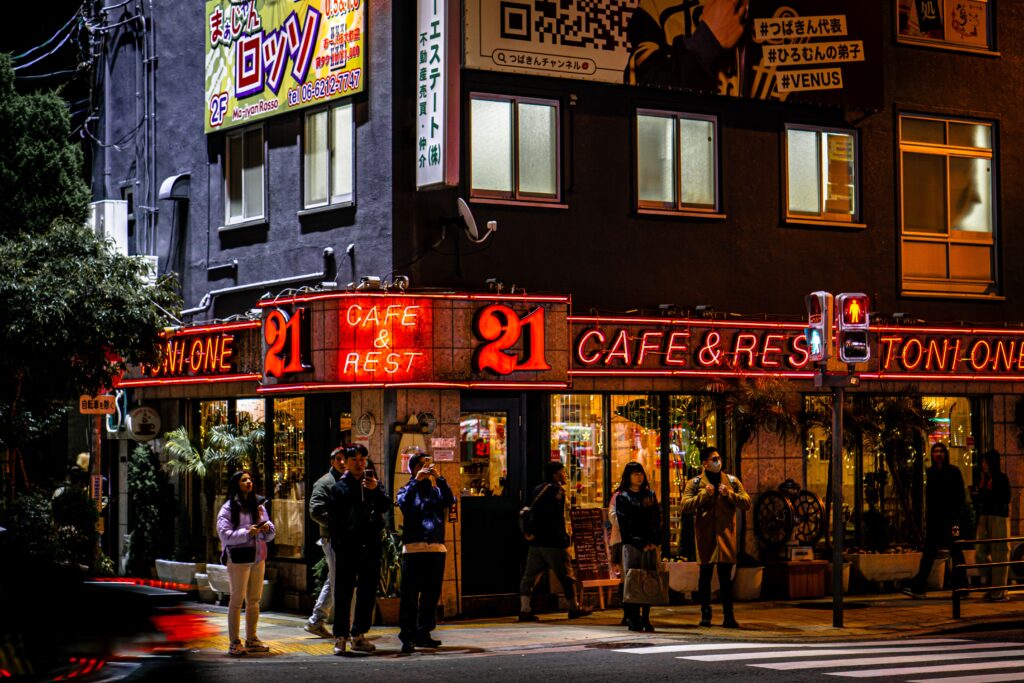 Vibrant city scene featuring a neon-lit café corner with people enjoying the nightlife.